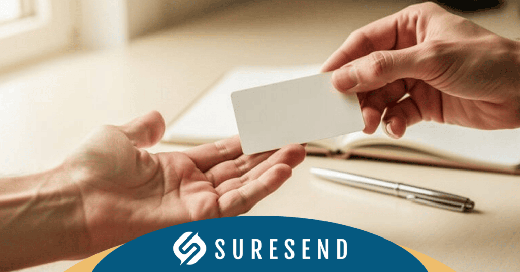 SEO-Friendly ALT Tag: SureSend CRM pricing comparison resource center image – person handing a blank white card to another individual, with notebook and pen ready for CRM insights, SURESEND logo visible. Caption: Evaluate CRM solutions efficiently—person exchanging a blank card with tools for noting down pricing insights at the SureSend CRM Resource Center. Description: This image from the SureSend CRM Resource Center shows one person handing a blank white card to another, emphasizing collaboration and information exchange when comparing CRM pricing options. A notebook and pen are placed beside them for jotting down important details during the decision-making process. The SURESEND logo is clearly displayed at the bottom, reinforcing brand presence throughout your research on optimal customer relationship management solutions.
