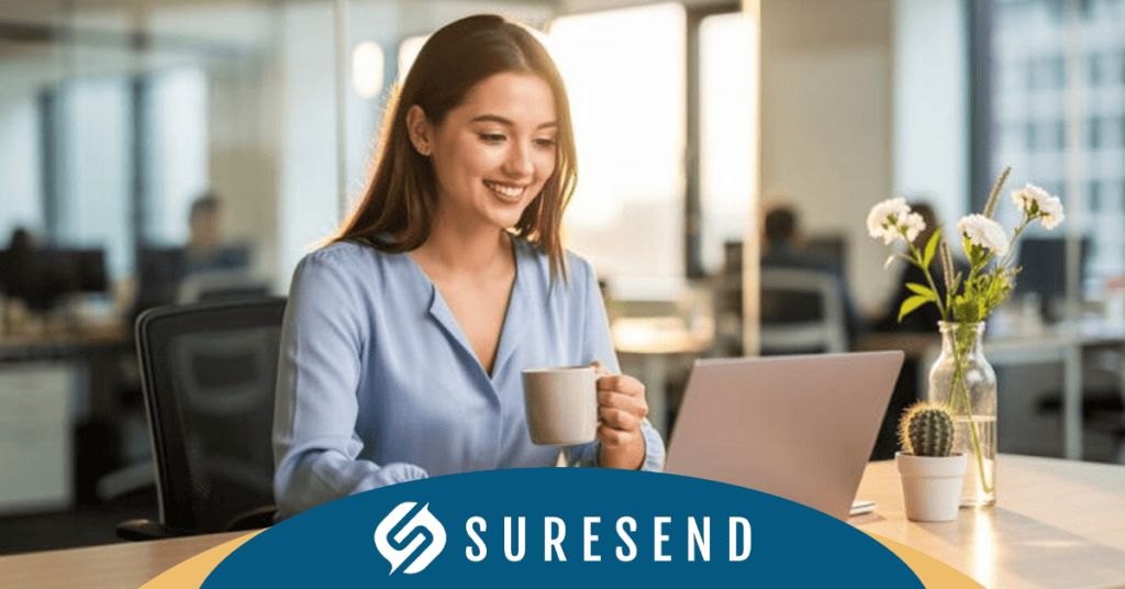 ALT tag: Woman reviewing CRM pricing comparison on laptop in modern office at Sure Send CRM Resource Center, with flowers, cactus, and Suresend logo. Caption: Smiling woman explores CRM pricing options at Sure Send CRM Resource Center—modern workspace with Suresend branding. Description: At the Sure Send CRM Resource Center, a professional woman sits in a contemporary office smiling as she holds a mug and assesses her laptop screen, likely comparing CRM pricing to choose the best platform. The desk features vibrant touches with a flower vase and cactus, contributing to an inviting environment. The Suresend logo visibly marks the image as part of the trusted SureSend.ai platform for optimal customer relationship management solutions.