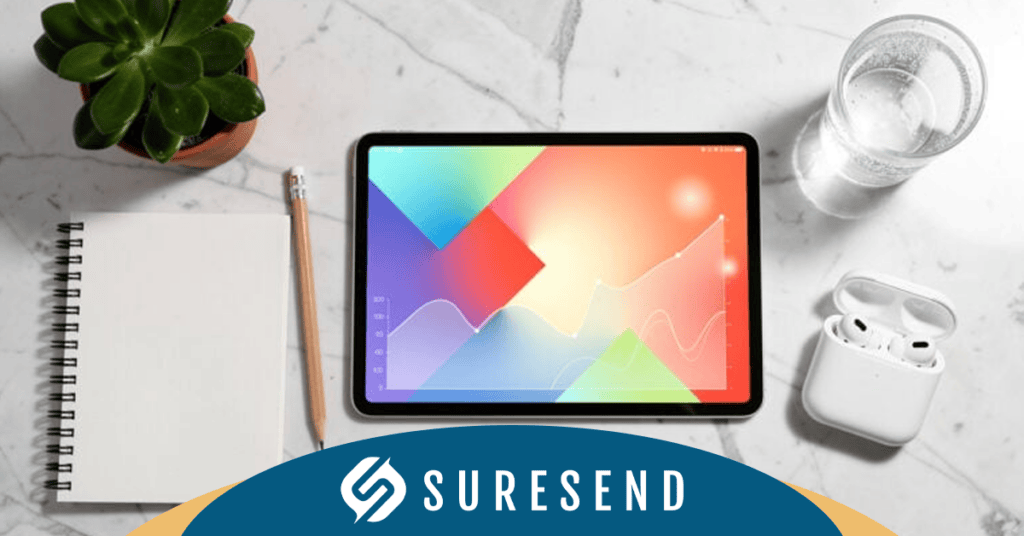 ALT tag: SureSend CRM pricing comparison data on tablet with graph, notebook, and office supplies on marble table. Caption: Analyze CRM pricing comparison with SureSend—tablet with graph and business tools at the Resource Center. Description: The Sure Send CRM Resource Center image shows a tablet displaying a colorful CRM pricing comparison graph on a marble table, accompanied by an open notebook, pencil, green plant, glass of water, and wireless earbuds. "SURESEND" appears at the bottom of the screen. This setup highlights data analysis tools for businesses comparing popular CRM platforms and solutions.